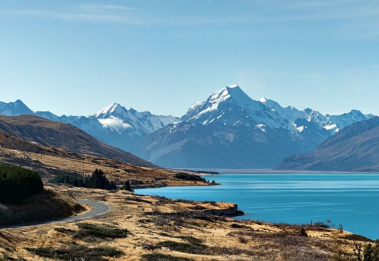 A road winds beside the blue lakes and alpine mountains of New Zealand