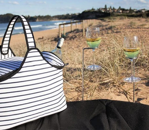 Picnic Setting on the beach with wine glass held in wine sticks in the sand